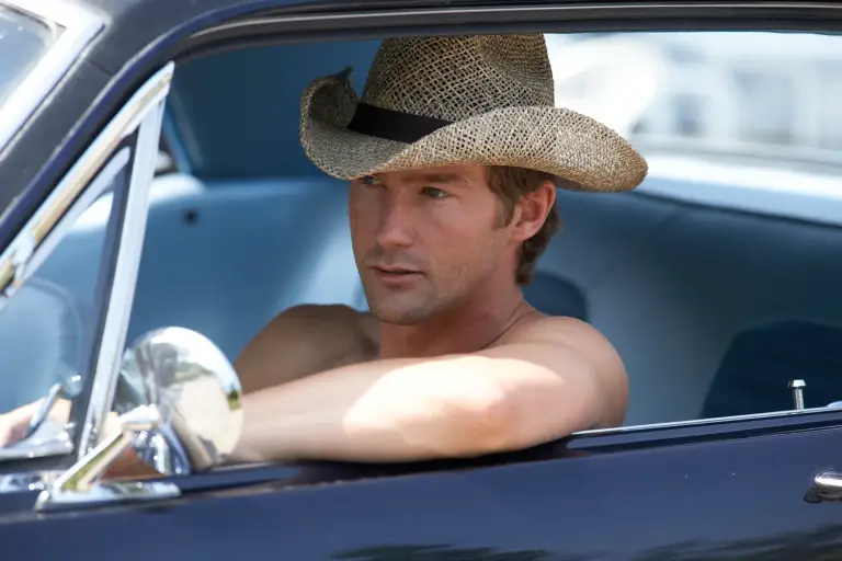 Mann mit Cowboyhut fährt lässig in einem Oldtimer